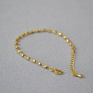 Detail of faceted gold bead bracelet with adjustable lobster clasp and drop pendant