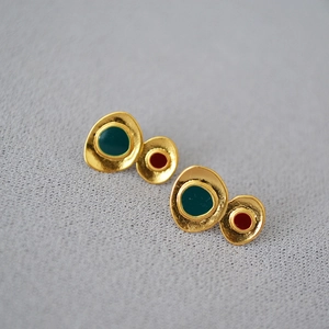 Detail of vintage geometric earrings with colorful enamel on textured knit background
