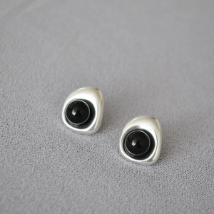 Detailed view of baroque silver earrings featuring minimalist black pearls and metal texture