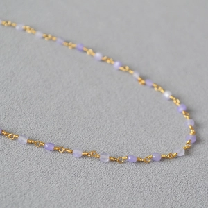 Detail of handmade gold wire-wrapped necklace with light purple translucent stones