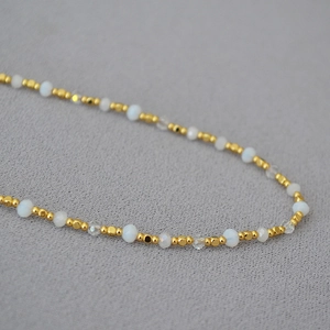 Detail of beaded necklace with gold brass, moonstone-style and faceted crystal beads