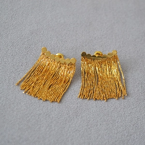 Détail de boucles d'oreilles à pampilles dorées avec fines chaînes et design minimaliste