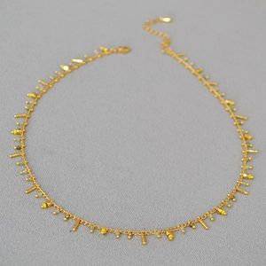 Detail of gold beaded necklace featuring turquoise accents and metallic fringe charms