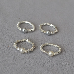 Detail of elastic beaded rings with irregular silver nuggets and white grey pearls