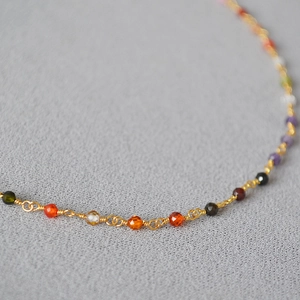 Macro shot of colorful faceted zircon beads on a fine gold-plated brass necklace chain