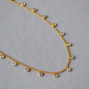 Detail of gold plated brass necklace featuring bezel-set round crystal pendants