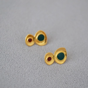 Artistic geometric gold-plated enamel earrings with red and green patterns on gray fabric