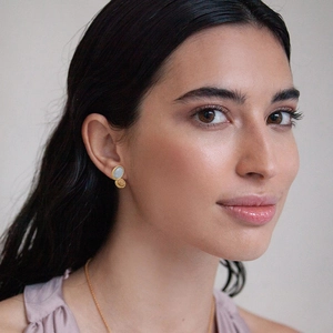 Vintage brass gold-plated stud earrings with blue and brown stone inlay on a female model