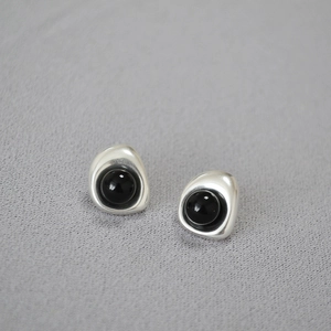 Detailed view of silver organic curved earrings with a round black onyx gemstone inlay
