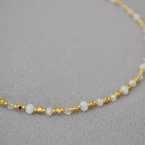 Macro detail of minimalist handmade beaded necklace with gold plated brass and glass beads