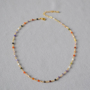 Detailed macro view of colorful faceted zircon beads on a thin gold-plated brass chain
