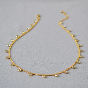 Detailed close-up of gold plated necklace featuring bezel-set round crystal zircon charms