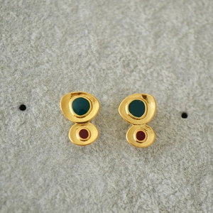 Macro view of geometric enamel earrings with abstract organic shapes in green and burgundy