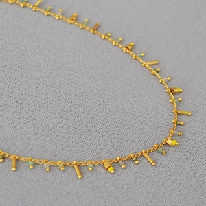 Detail of bohemian gold chain necklace with colorful beads and sleek metallic bars