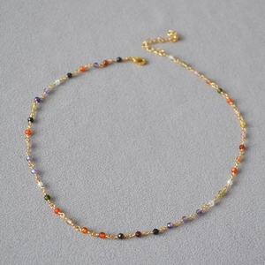Close-up of colorful faceted beads on a delicate gold-plated brass chain necklace