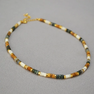 Détail d'un collier de perles colorées avec séparateurs dorés et fermoir mousqueton doré