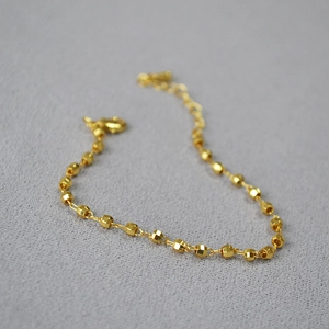 Detailed close-up of shiny faceted laser football beads on a gold-plated brass bracelet