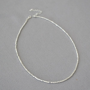 Gros plan du collier ras du cou minimaliste en perles argentées avec fermoir et extension