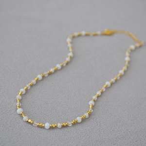 Detail of beaded necklace with gold brass beads, opal stones and crystal faceted beads