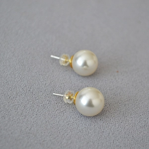 Minimalist 925 silver needle pearl stud earrings with clear silicone backs on grey fabric