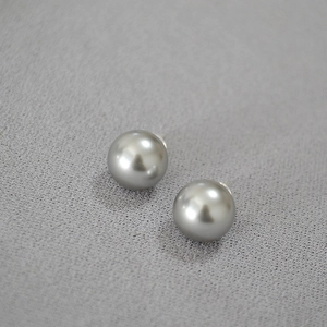 Détail de boucles d'oreilles en argent 925 avec perles grises sur fond textile gris