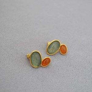 Detailed close-up of brass gold-plated earrings with green and orange stone inlay