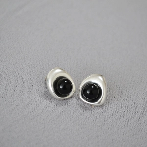 Macro view of minimalist silver earrings featuring organic metal lines and black pearls