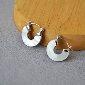 Détail de boucles d'oreilles créoles en argent avec incrustation de nacre blanche