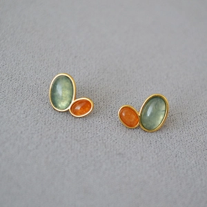 Detail view of retro gold-plated earrings with green and orange gemstone inlay