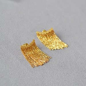 Détail de boucles d'oreilles dorées à pampilles avec chaînes fines et aiguille en argent 925