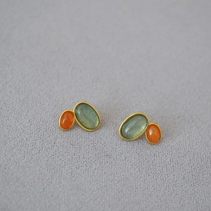 Macro detail of vintage gold-plated studs with inlaid green and red gemstones
