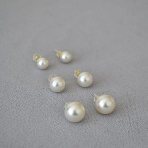 Three pairs of white pearl earrings in different sizes with gold-plated silver needles