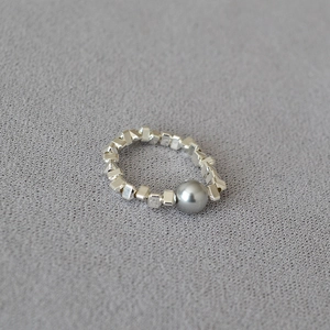 Close-up of minimalist silver geometric beaded ring with a dark grey pearl centerpiece