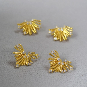 Dettaglio macro di orecchini vintage dorati con design a raggiera e cristalli di zircone