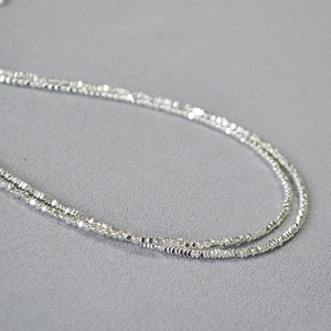 Vue détaillée d'un collier de perles argentées à facettes avec un éclat métallique brillant