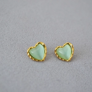 Détail macro de boucles d'oreilles cœur en œil de chat avec bords festonnés dorés