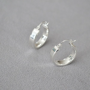 Gros plan de boucles d'oreilles créoles larges en argent poli avec finition miroir
