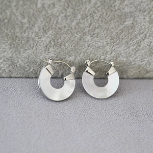 Vue détaillée des boucles d'oreilles argentées avec incrustation de nacre irisée blanche