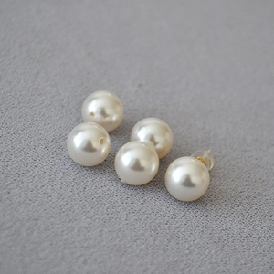 Detailed macro view of 925 silver pearl stud earrings and round cream-colored beads