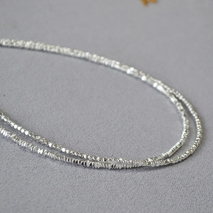 Vue macro de perles argentées facettées sur un collier fin avec texture étincelante