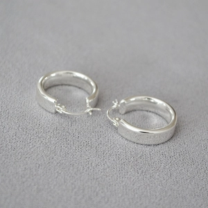Gros plan de boucles d'oreilles créoles larges en argent poli avec finition miroir brillant