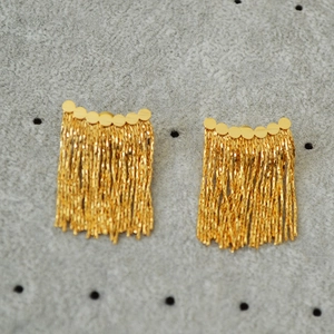 Détail de boucles d'oreilles dorées avec chaînes à franges et paillettes rondes brillantes