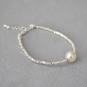 Detail of silver beaded bracelet with irregular facets and a single white pearl accent
