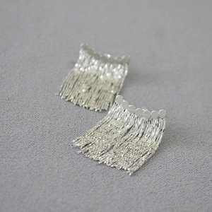 Gros plan de boucles d'oreilles minimalistes à pampilles argentées et longues chaînes