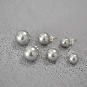 Vue détaillée de boucles d'oreilles perles gris argent de tailles variées sur tissu