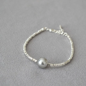 Macro detail of high-luster grey pearl on a faceted silver bead bracelet with adjustable chain