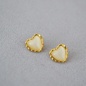Détail des boucles d'oreilles cœur en pierre œil-de-chat avec bords ondulés dorés
