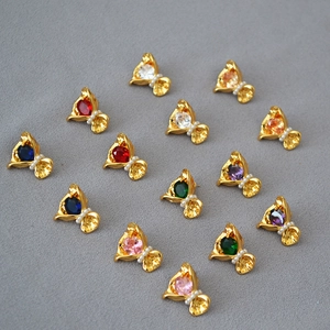 Vue à plat de 14 paires de boucles d'oreilles papillon en zircon coloré en laiton plaqué or