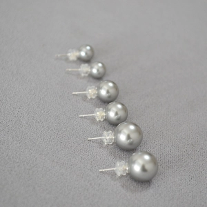Détail macro de boucles d'oreilles perles grises sur tissu avec tiges en argent