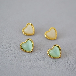 Détail de boucles d'oreilles cœur vintage avec bords dorés en coloris crème et menthe
